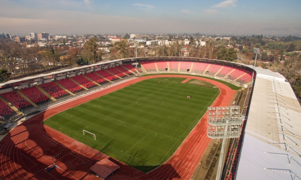 Aerial view eines Fußballstadions, das ein lebhaftes Spielfeld und volle Tribünen zeigt.